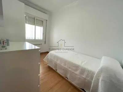 a white bedroom with a bed and a window at O cuarto de abastos in Ourense