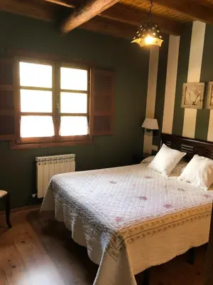 a bedroom with a large bed and two windows at Apartamentos Rurales CASONA DE LOLO in Caunedo
