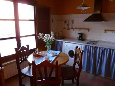 a kitchen with a table and chairs and a kitchen with a sink at Apartamentos Rurales CASONA DE LOLO in Caunedo