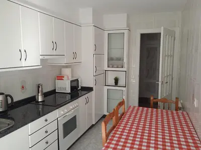 a kitchen with white cabinets and a table and a microwave at O Refuxio de Sigüeiro # a 10 min de Santiago in Sigüeiro