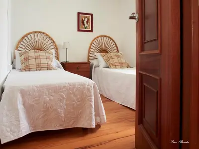 a bedroom with two beds and a wooden floor at Casa de Mila en Creciente Pontevedra in Crecíente