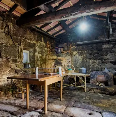a room with a table and chairs in a stone wall at Casa de Mila en Creciente Pontevedra in Crecíente