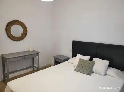 a bedroom with a white bed with a black headboard and a mirror at Casa Dina in Carballino