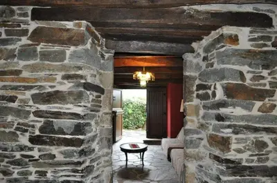 a stone hallway with a stone wall and a chandelier at A Horta de Abel in Tríacastela