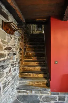 a staircase in a stone building with a red wall at A Horta de Abel in Tríacastela