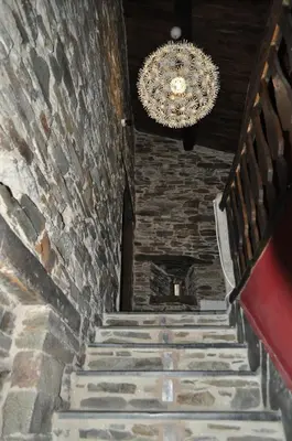 a chandelier and stairs in a building with a stone wall at A Horta de Abel in Tríacastela