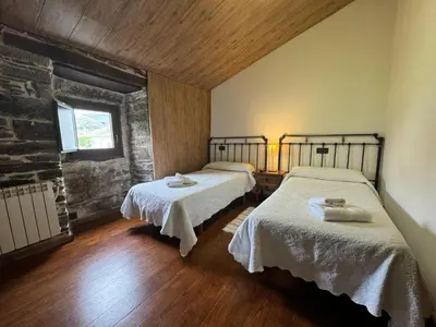 a bedroom with two beds with white linens at A Horta de Abel in Tríacastela