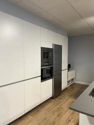 a kitchen with white cabinets and a stainless steel refrigerator at Fogar de Aurora in Portomarin