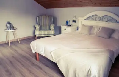 a bedroom with a large white bed and a chair at O Lagoeiro in A Estrada