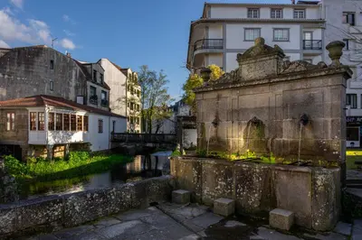 a bridge over a river in a city with buildings at FondeRiviere in Caldas de Reis
