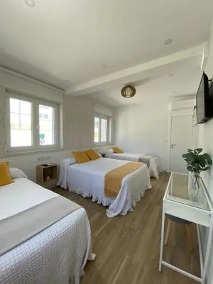 a hotel room with three beds and a television at PortoSantiago Boutique & Rooms in Portomarin