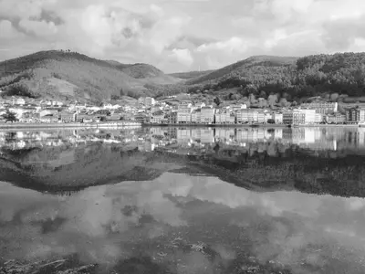 a black and white photo of a city next to a lake at The Cliffs - Montmar in Viveiro