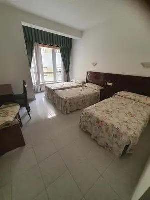 a hotel room with two beds and a window at Flor de Loto in Ordes