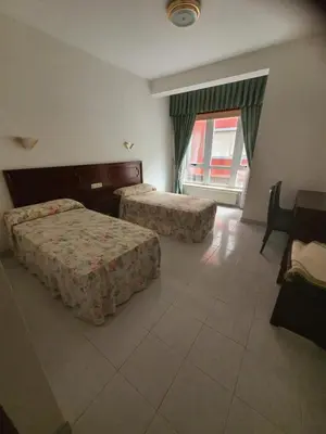 a hotel room with two beds and a window at Flor de Loto in Ordes