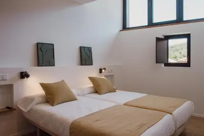 two beds in a room with two windows at Casiñas do Sil in Cristosende