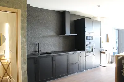 a kitchen with black cabinets and a white refrigerator at Hotel Casas da Fortaleza in Lugo