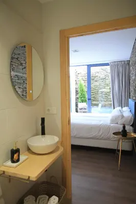 a bathroom with a sink and a bed and a mirror at Hotel Casas da Fortaleza in Lugo