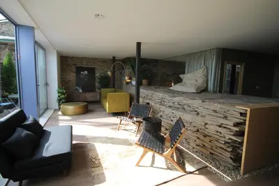 a living room with chairs and a stone wall at Hotel Casas da Fortaleza in Lugo