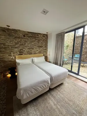 a bedroom with a large bed and a brick wall at HOTEL CASAS DA FORTALEZA Casa da Muralla in Outeiro de Rei
