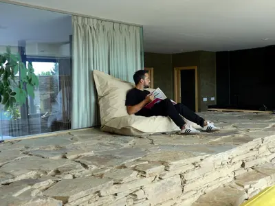 a man sitting on a pillow reading a book at HOTEL CASAS DA FORTALEZA Casa da Muralla in Outeiro de Rei