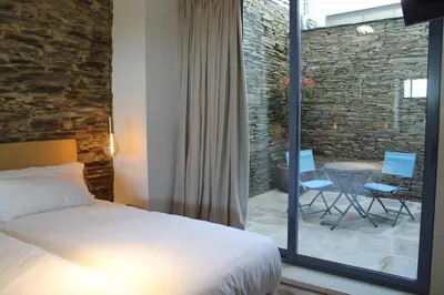 a bedroom with a bed and a table and chairs at HOTEL CASAS DA FORTALEZA Casa da Muralla in Outeiro de Rei