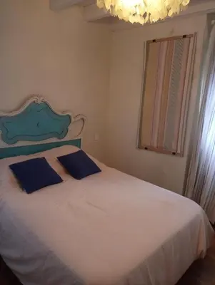 a bedroom with a white bed with two blue pillows at VILLA OLIMAR in San Juan de Prendones