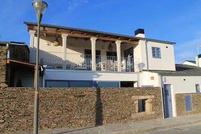 a white house with a stone wall and a street light at HOTEL CASAS DA FORTALEZA Casa da Solaina in Outeiro de Rei