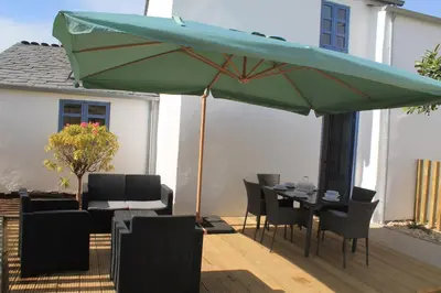 a patio with a table and a green umbrella at HOTEL CASAS DA FORTALEZA Casa do Garda in Outeiro de Rei