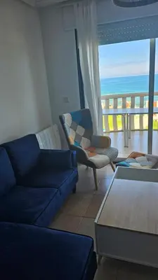 a living room with a couch and chairs and a view of the ocean at Apartamento Oceano in Barreiros