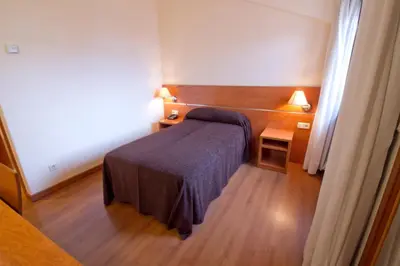 a small bedroom with a bed and a night stand at Hotel Torques in A Coruña