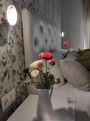 a vase with flowers on a table next to a bed at La Casa del Camino in Santiago de Compostela