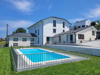 a swimming pool in front of a house at Apartamentos Casona del Campo in Navia