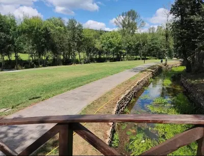 a wooden bench next to a river in a park at Piso turístico Baralla in Baralla
