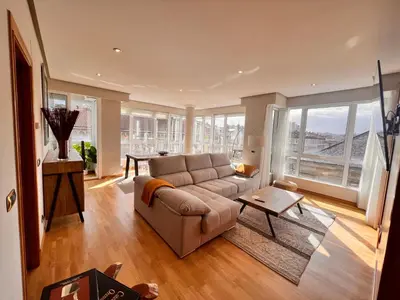 a living room with a couch and a large window at Apartamentos San Martín Ourense Centro 1 in Ourense