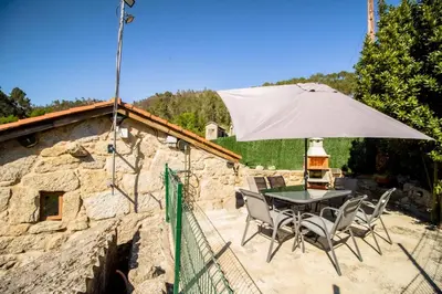 a patio with a table and chairs and an umbrella at A Casiña dos Canastros in Barcia