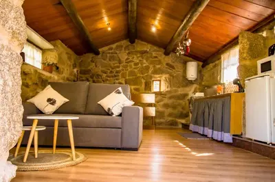a living room with a couch and a stone wall at A Casiña dos Canastros in Barcia