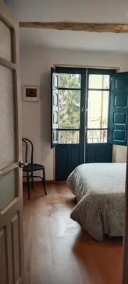 a bedroom with a bed and two windows and a door at El Volante Alojamiento Turístico in Villafranca del Bierzo