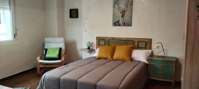 a bedroom with a large bed and a chair at El Volante Alojamiento Turístico in Villafranca del Bierzo