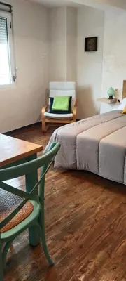 a room with two beds and a chair and a table at El Volante Alojamiento Turístico in Villafranca del Bierzo