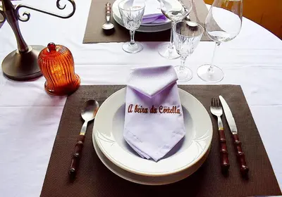 a plate with a napkin on a table with silverware at A Beira da Cortella in Melón