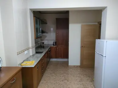 a kitchen with wooden cabinets and a white refrigerator at Piso centrico en Ribadeo in Ribadeo