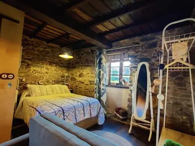 a bedroom with a bed and a stone wall at Casita de Florita in Doade