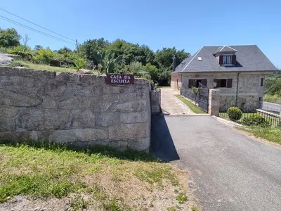 a stone wall with a sign on it next to a house at Casa da Escuela in Caldas de Reis