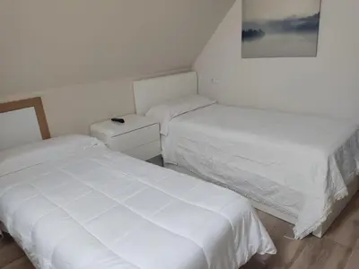two beds in a small room with white sheets at Casa da Escuela in Caldas de Reis
