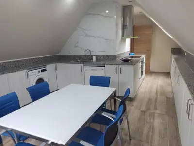 a kitchen with a table and blue chairs at Casa da Escuela in Caldas de Reis
