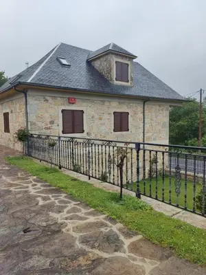 a stone house with a black fence in front of it at Casa da Escuela in Caldas de Reis