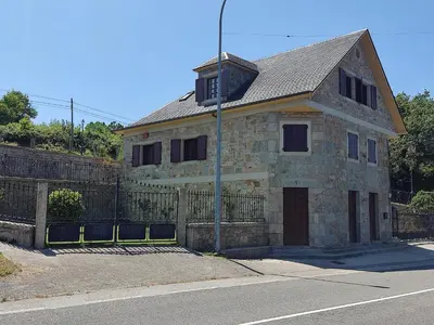 an old stone house on the side of a street at Casa da Escuela in Caldas de Reis