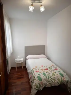 a bedroom with a bed and a table and a window at PISO OROSO NO CAMIÑO in Sigüeiro