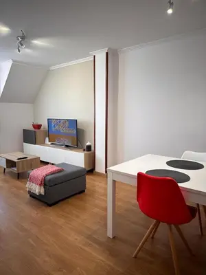 a living room with a white table and a red chair at PISO OROSO NO CAMIÑO in Sigüeiro