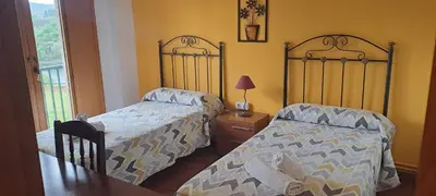 a bedroom with two beds and a table with a lamp at Pensión Boavista in Portomarin